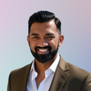 Minto Michael, Eddy House Program Quality & Data Director, smiling in a brown suit jacket and white shirt against a soft pastel background.