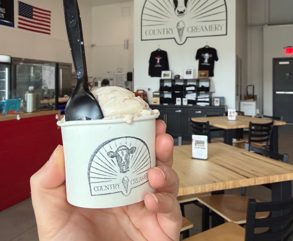 Hand holding a cup of Country Creamery ice cream inside the Reno ice cream shop, part of the Alpha Phi Omega fundraiser benefiting Eddy House.