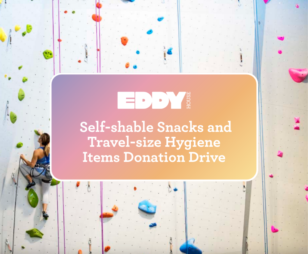 Climber on the Mesa Rim Reno climbing wall with Eddy House donation drive graphic for shelf-stable snacks and travel-size hygiene items.